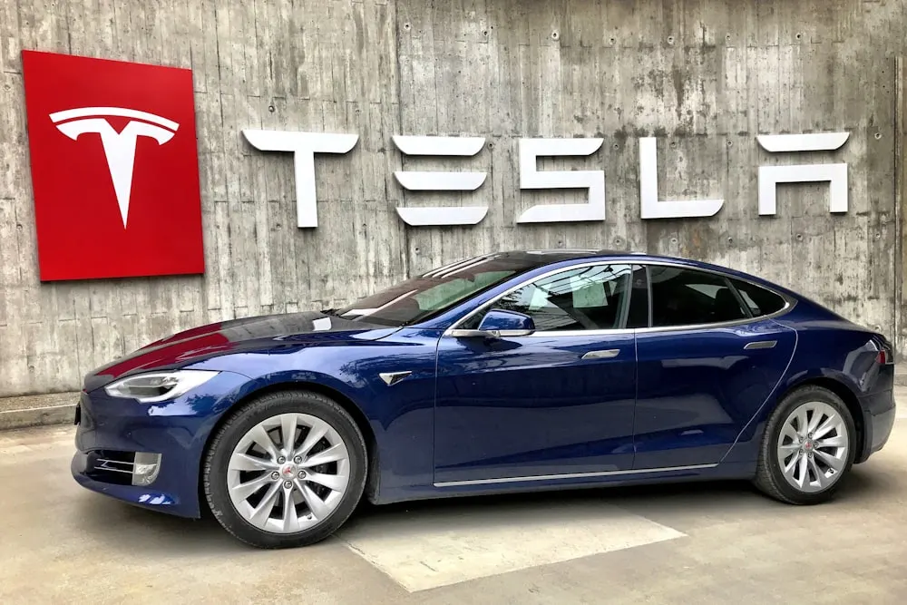 coupé bleu garé à côté d'un mur blanc