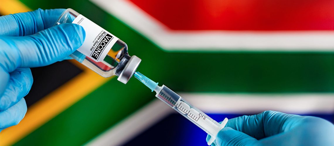 Doctor preparing vial of vaccine injection generic for the vaccination plan against diseases in South Africa. Injecting dose of vaccine in syringe for contagious diseases prevention in front of the South Africa flag