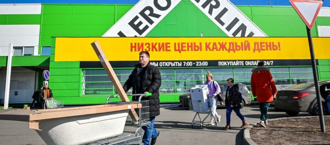 A man carries his goods at a parking lot in front of a French hardware and gardening store Leroy Merlin which continues to work in Russia despite the sanctions, in the town of Klimovsk outside Moscow on March 19, 2022. - On February 24, Russian President ordered Russian troops to pour into pro-Western Ukraine, triggering unprecedented Western sanctions against Moscow and sparking an exodus of foreign corporations. (Photo by AFP)