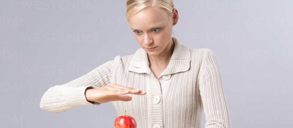 Young woman looking at flying apple