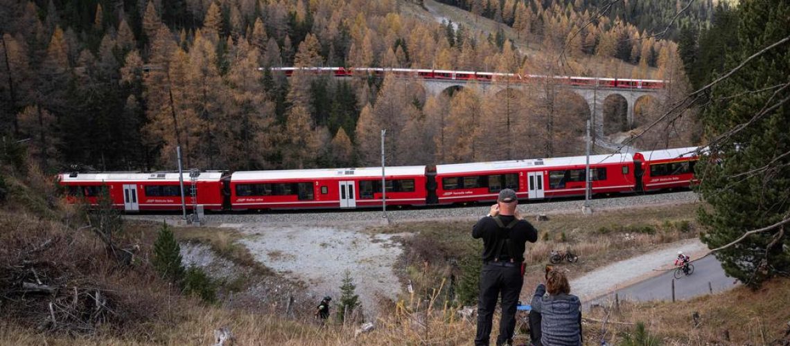 Members of the public capture images as a 1910-metre-long train with 100 cars passes near Bergun, on October 29, 2022, during a record attempt by the Rhaetian Railway (RhB) of the World's longest passenger train, to mark the Swiss railway operator's 175th anniversary. - The record attempt is carried out on the Albula Line, from Preda to Thusis, crossing one of the most spectacular railways in the world, recognised as a Unesco World Heritage Site. (Photo by Fabrice COFFRINI / AFP)